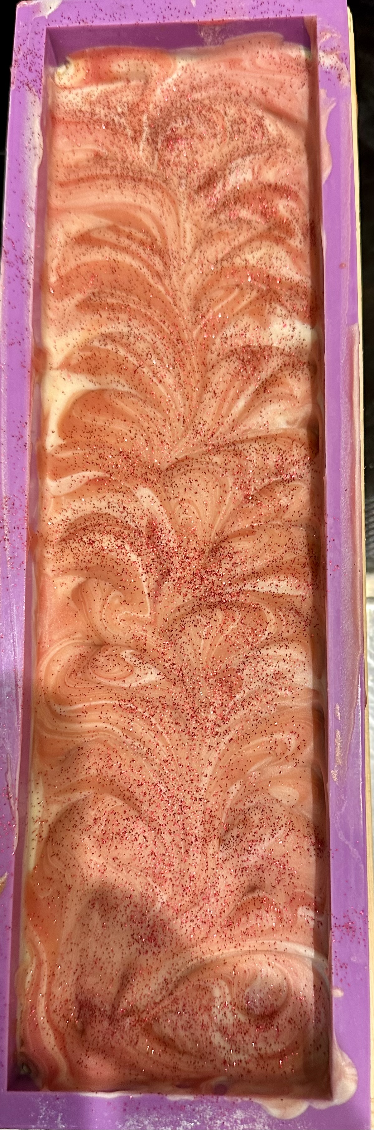 A pink swirled soap loaf fresh from the mold